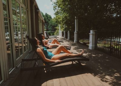 Two women laying in the sun on a deck